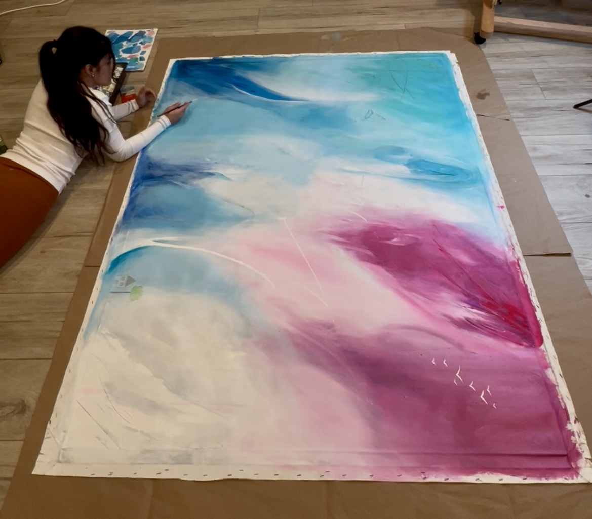Karin Rave working on the floor of her studio beside a large unfinished canvas